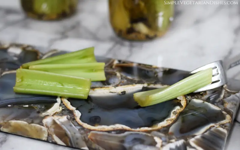 four fermented celery sticks served on gray agate cheese board