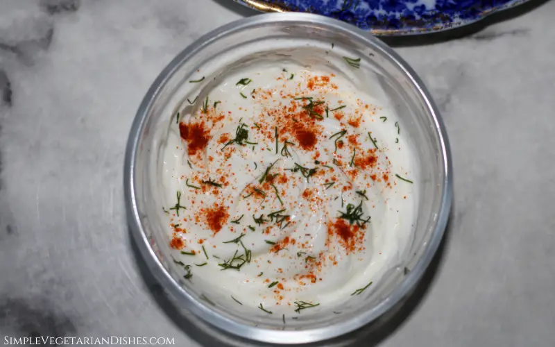 Greek yogurt dip in small glass bowl with lemon garlic dill paprika
