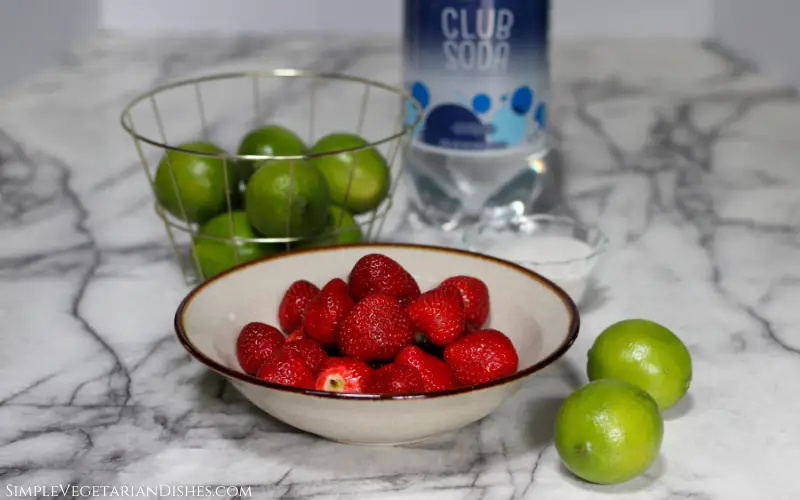 berries and limes with sugar and club soda on white marble table