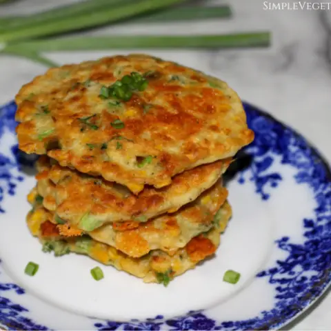 four gluten-free corn fritters stacked on a blue china plate