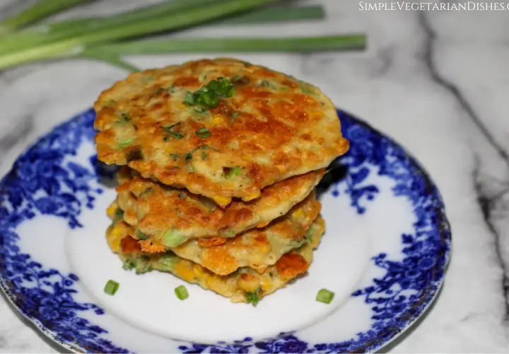 four gluten-free corn fritters stacked on a blue china plate
