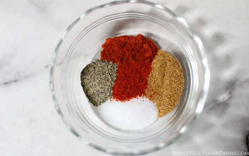 small glass bowl with salt pepper paprika cayenne and cumin