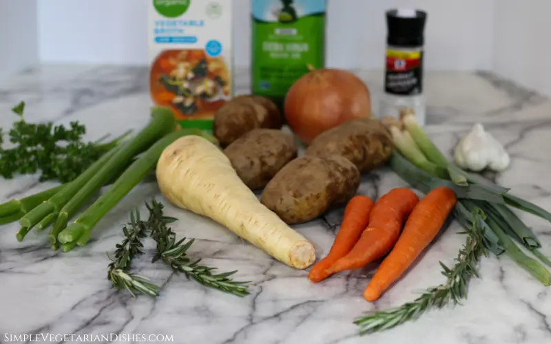 parsnip, carrots, potatoes, celery, leeks, parsley, rosemary, garlic, vegetable broth, olive oil, salt on white marble table