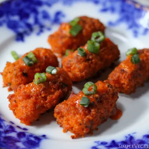 baked buffalo tofu wings served on blue china with green onions