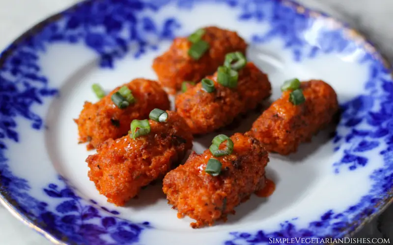 baked buffalo tofu wings served on blue china with green onions