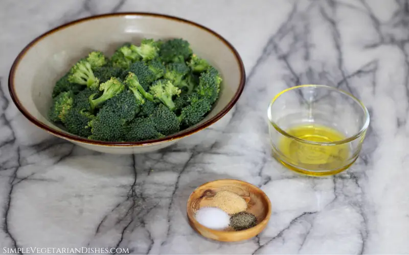 ingredients for air frying fresh broccoli in bowls on white marble table