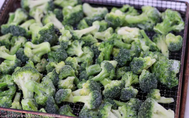 layer of frozen broccoli in air fryer metal basket before cooking