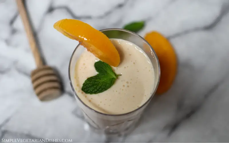 banana peach smoothie close up with honey dipper in background