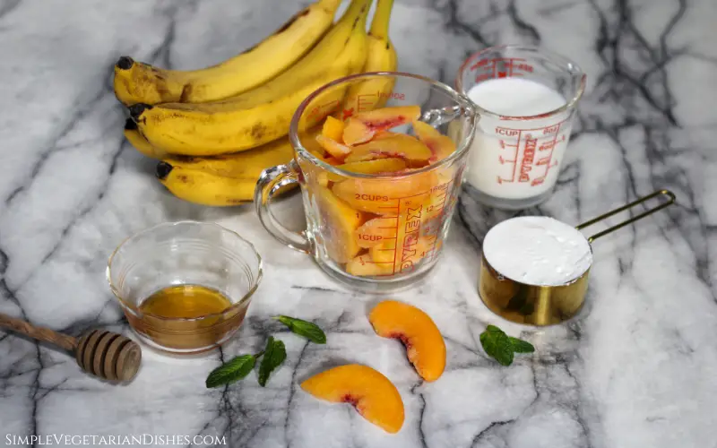 frozen and fresh fruit, milk, Greek yogurt, mint and honey on white marble table