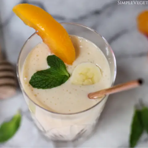banana peach smoothie garnished with banana, peach, and mint close up