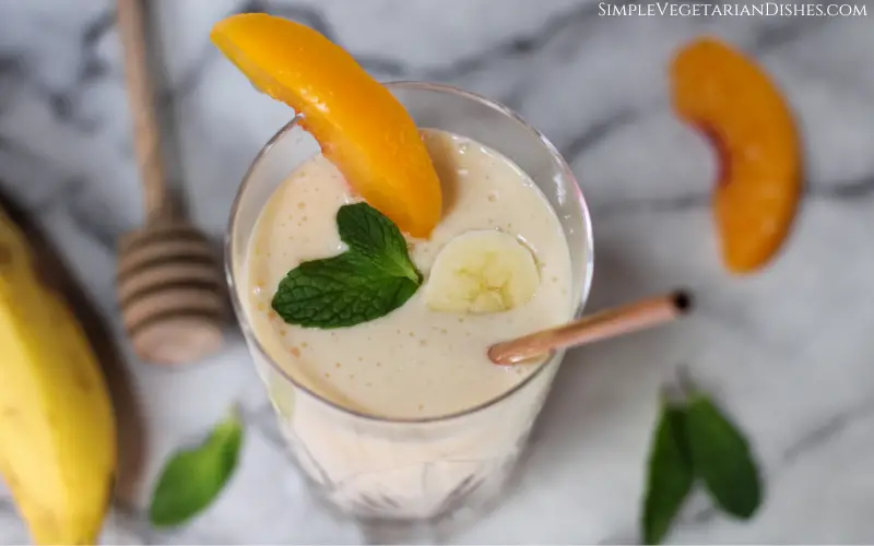 banana peach smoothie garnished with banana, peach, and mint close up