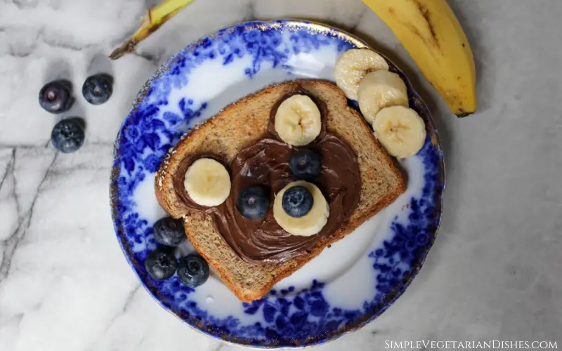 teddy bear toast with nutella and fresh fruit on blue china plate