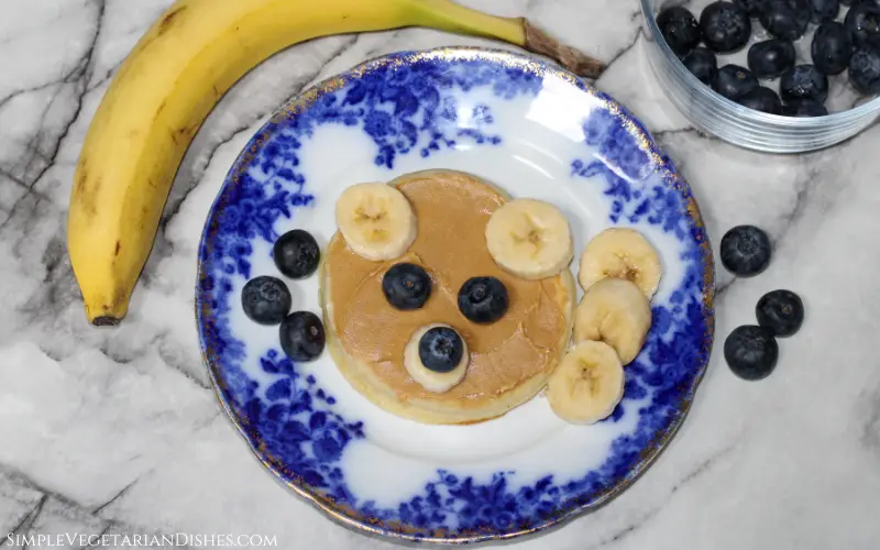 teddy bear waffle with peanut butter and fresh fruit on blue china plate