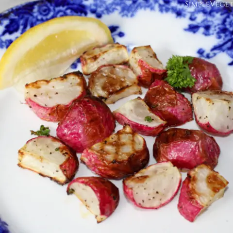 blue plate of air fryer radishes with parsley and a lemon wedge