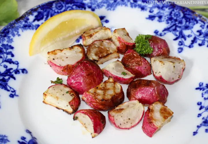 blue plate of air fryer radishes with parsley and a lemon wedge