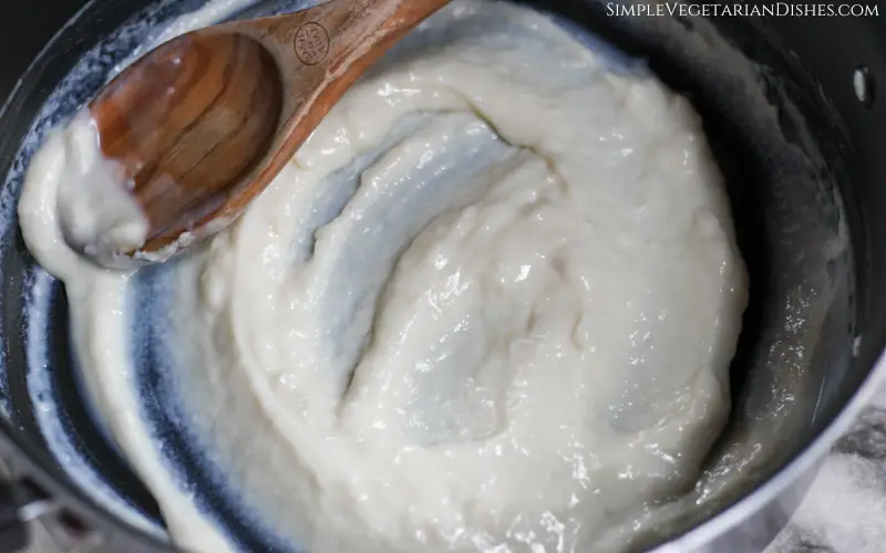 vanilla icing being cooked in dutch oven with wooden spoon