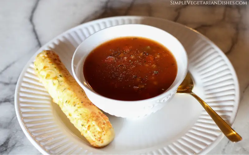 breadstick served with bowl of soup on white dishes