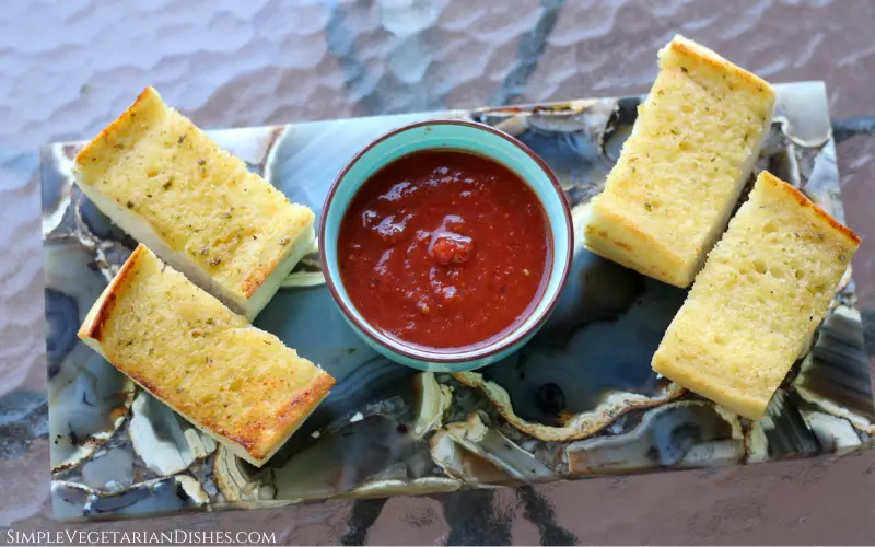 frozen garlic bread in air fryer served with tomato sauce on gray agate cheese board