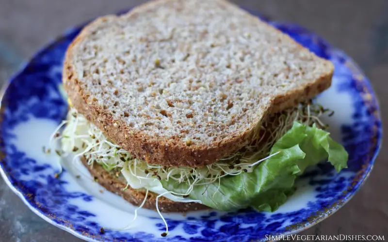 is Ezekiel bread keto sandwich with sprouts and lettuce on blue china plate