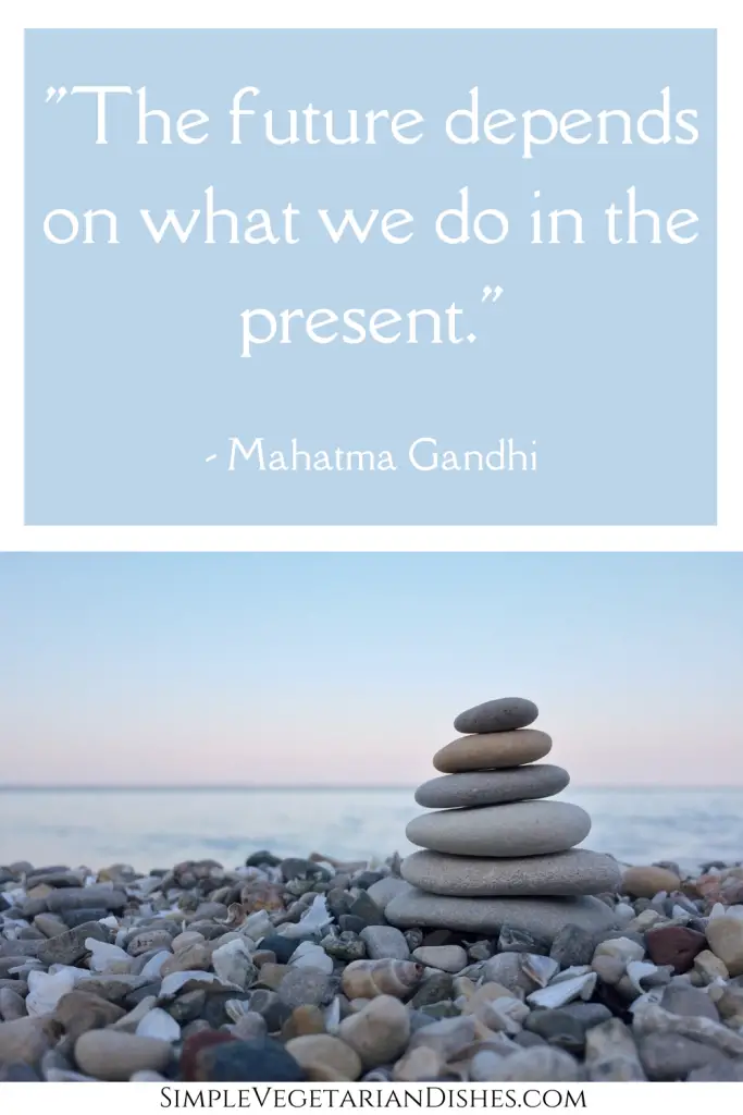 mahatma gandhi quote with stack of balanced smooth flat rocks on rocky beach
