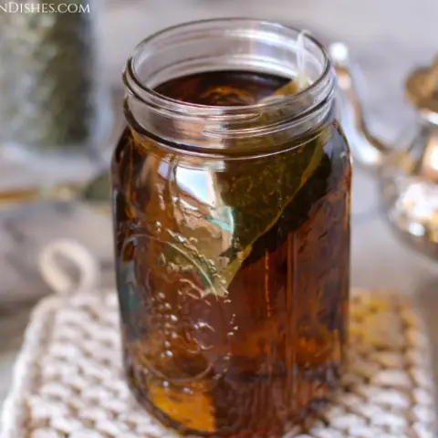 health benefits of nettle tea image large mason jar of nettle tea with teapot in background