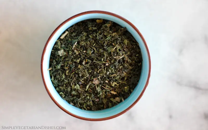 dried urtica dioica leaves in blue ceramic bowl