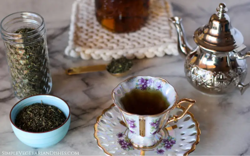 health benefits of nettle tea image ceramic floral teacup full of nettle tea with pot in background