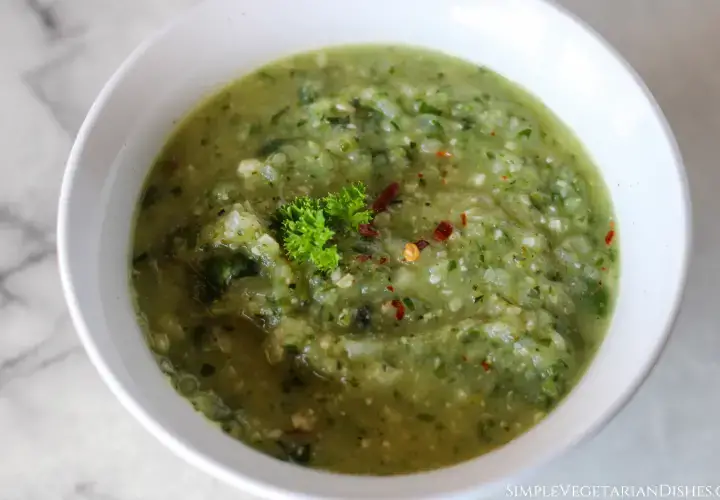 vegan spicy zucchini soup in white bowl with parsley garnish